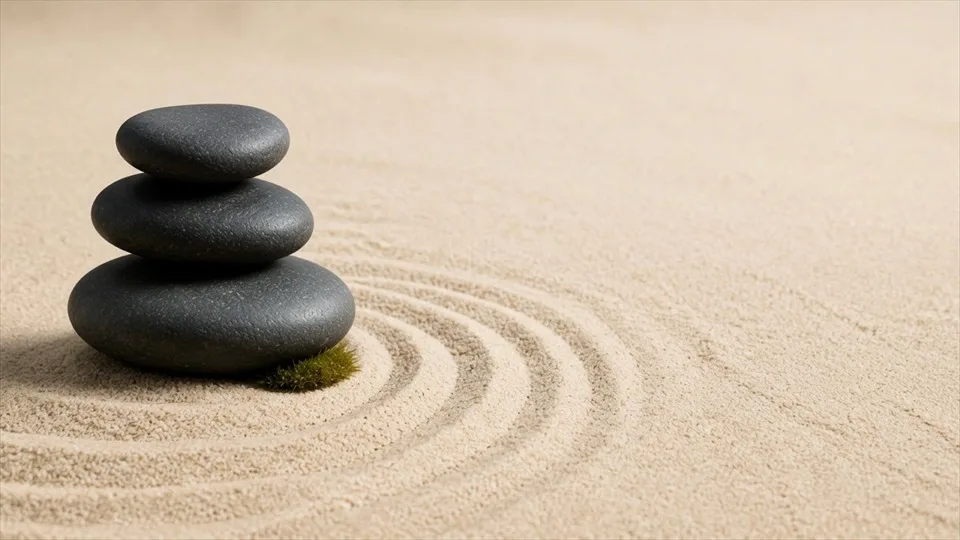 Piedras equilibradas descansan en un sereno jardín de arena.